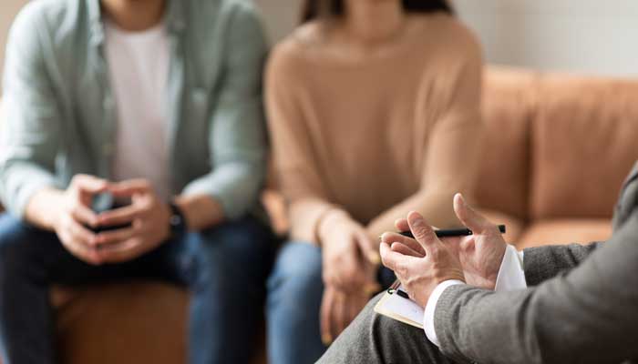 Couple sitting on couch during therapy session, talking to counselor