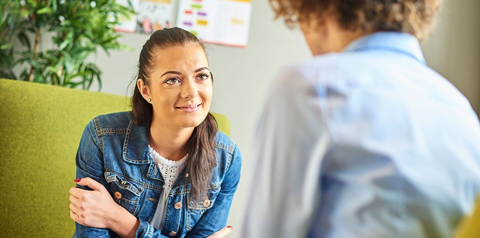A woman engages in conversation with a man in a professional office setting.