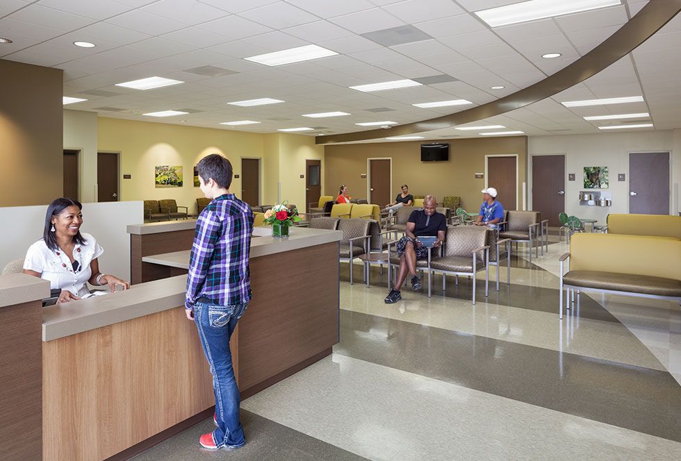 A hospital lobby featuring individuals seated at the reception desk, with a welcoming atmosphere and modern decor.