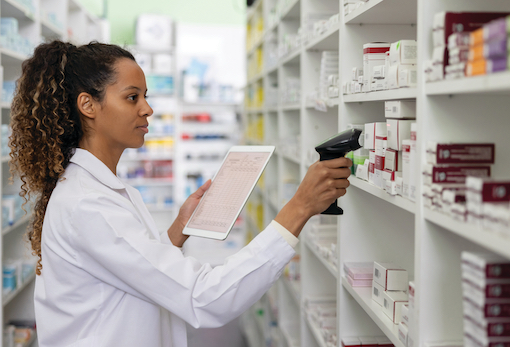 A pharmacist scanning medications on a shelf